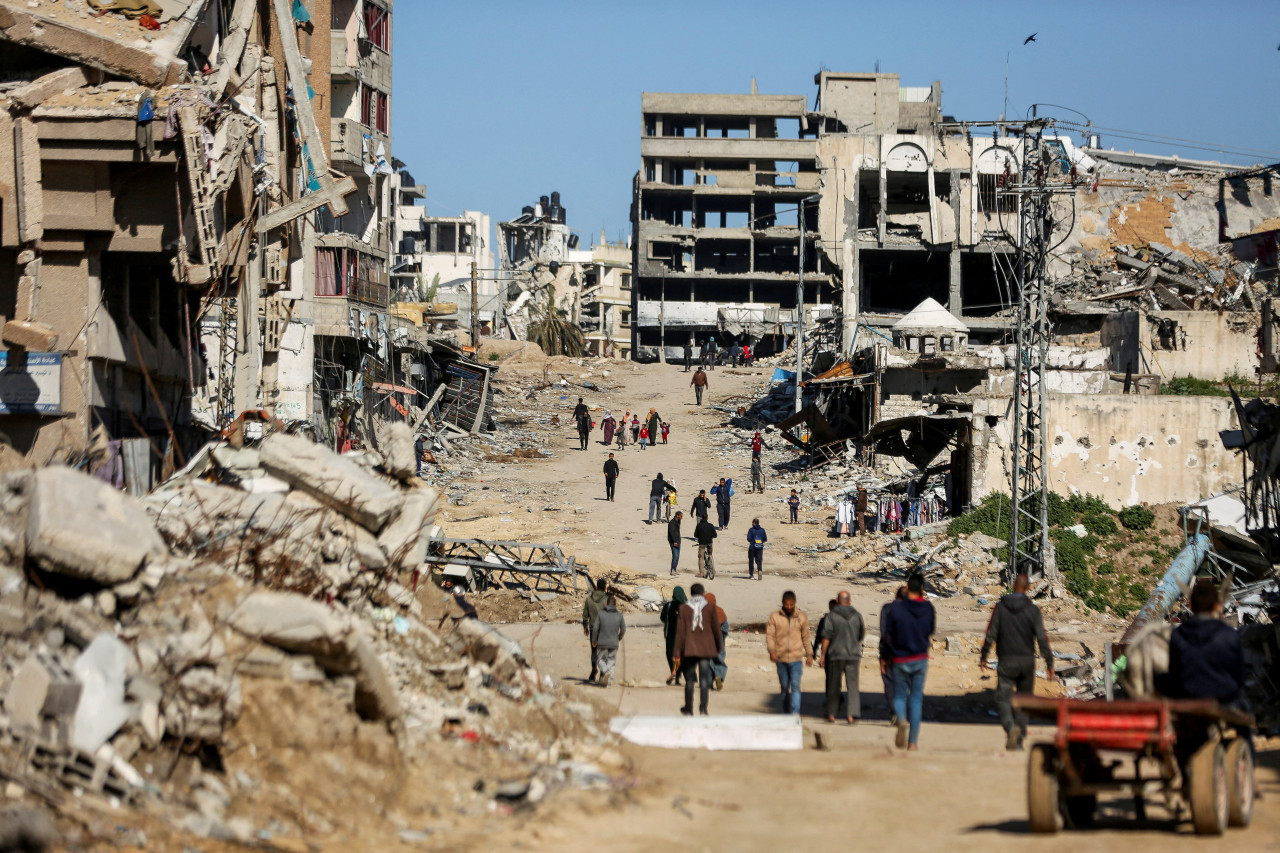Palestinos caminan junto a las ruinas de las casas destruidas durante la ofensiva militar de Israel. Reuters